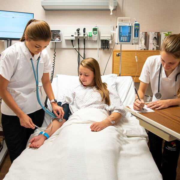 Three nursing students simulate working in a hospital.